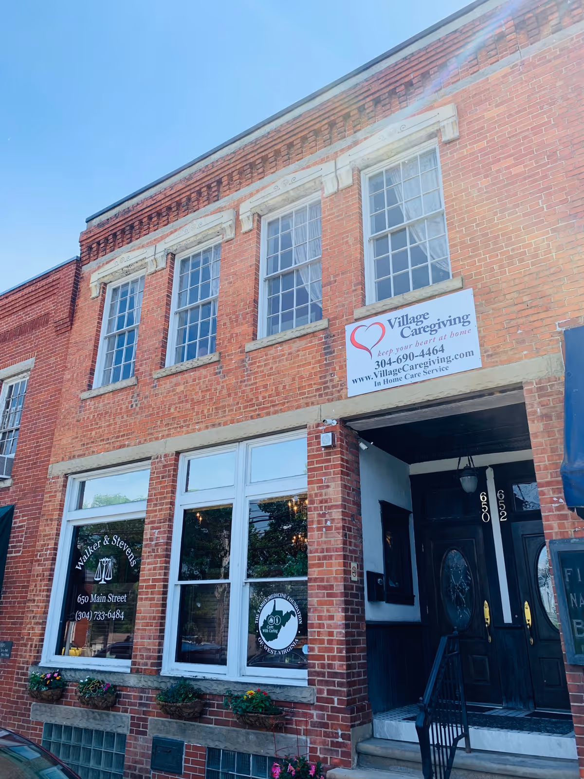 Brick building exterior featuring Village Caregiving sign and a dark entrance doorway.