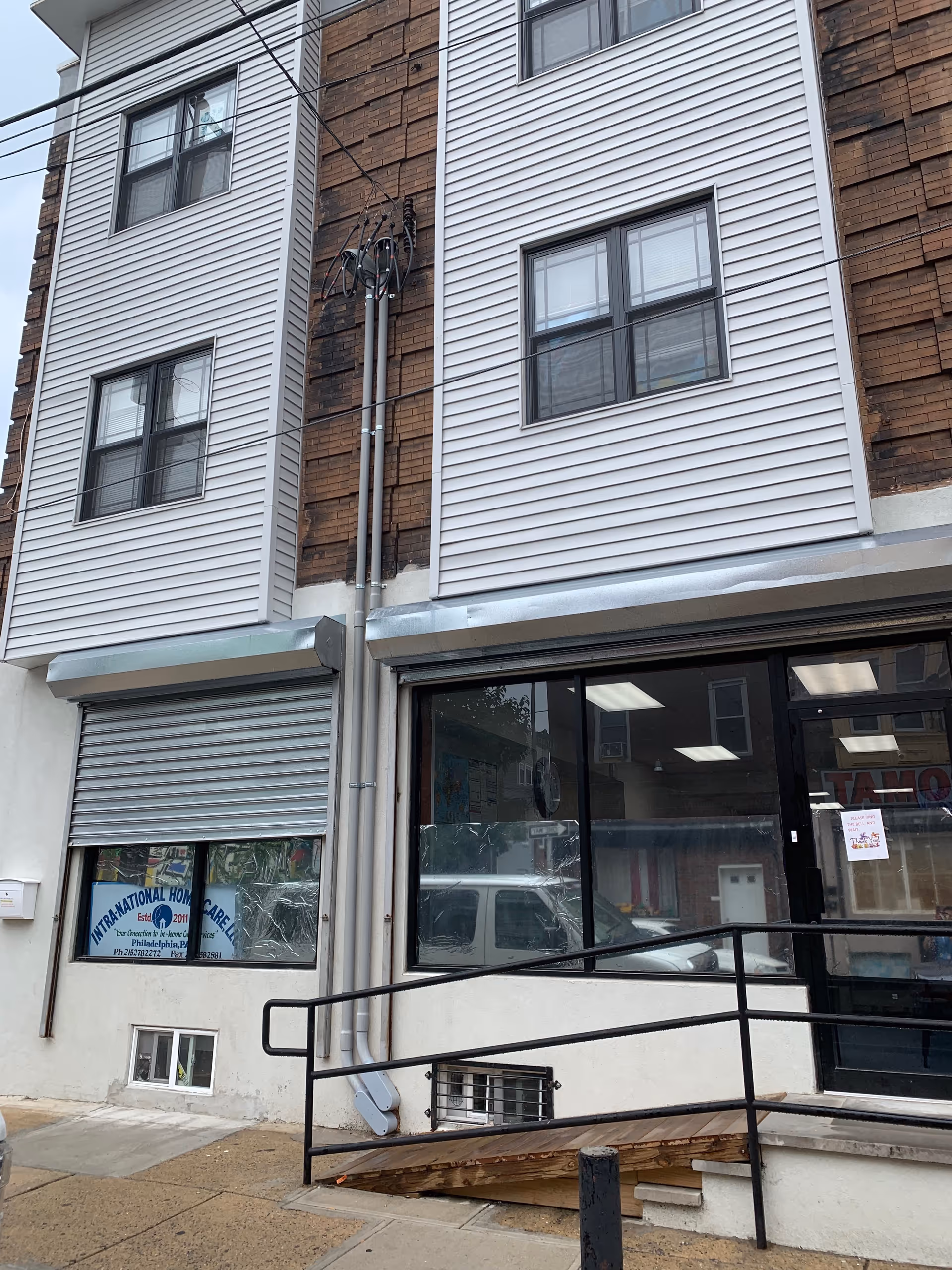 Exterior view of a multi-story building with a storefront entrance and ramp.