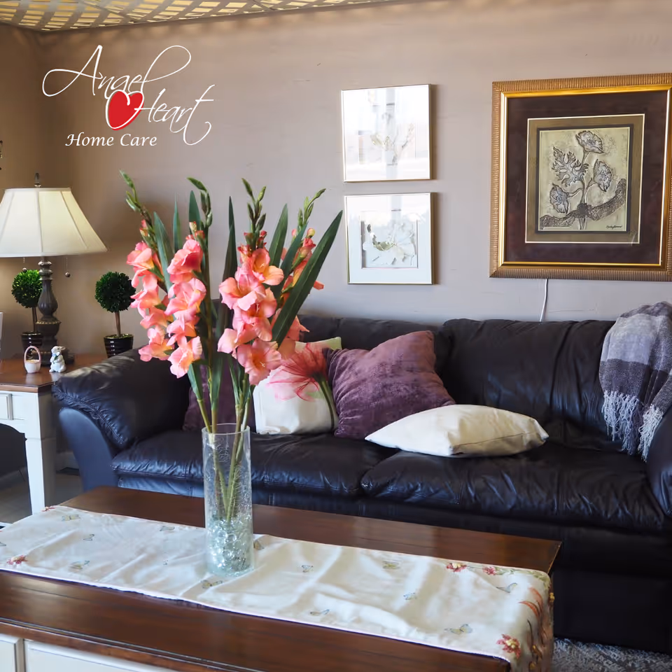 Cozy living room with a leather sofa, vases of pink flowers, and wall art.
