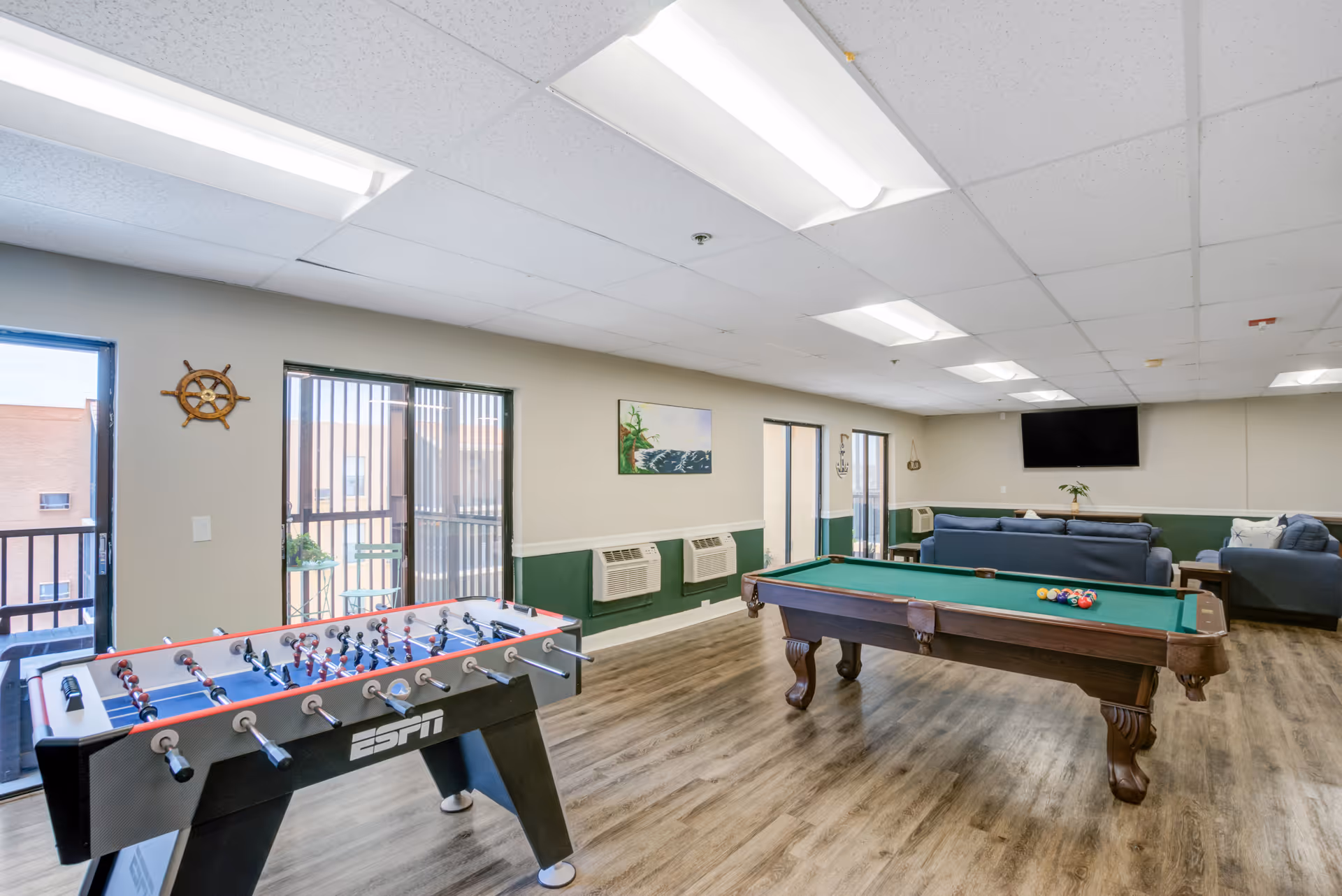 Interior recreation room in a senior living facility with pool table, foosball, and seating.