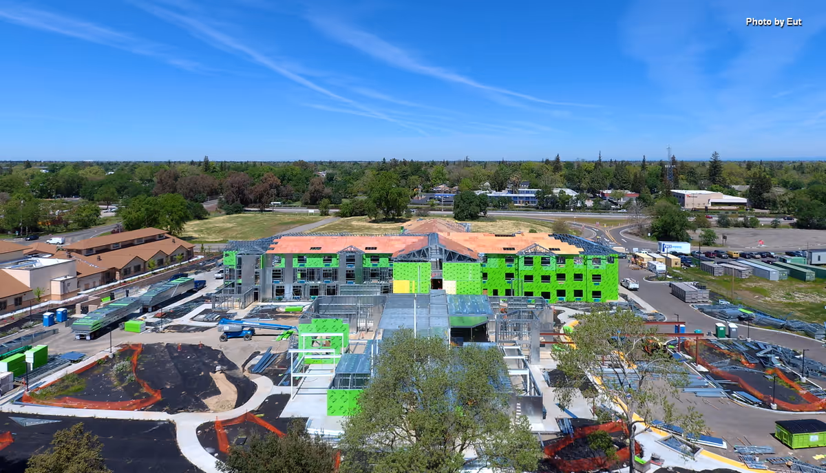 Aerial view of a large building under construction with bright green exterior panels.