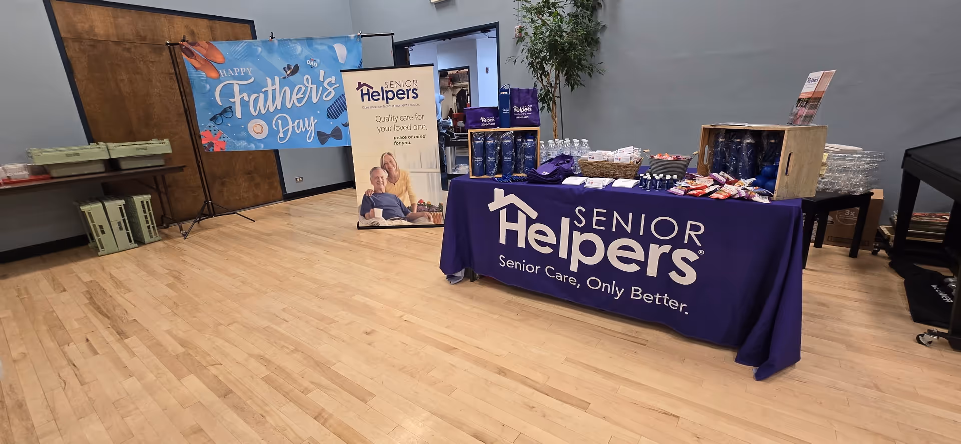 Indoor event setup with Senior Helpers banner, table, and promotional materials.