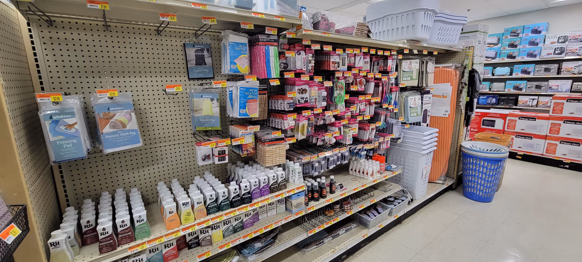 Interior store aisle with cleaning supplies and household items on metal shelves.