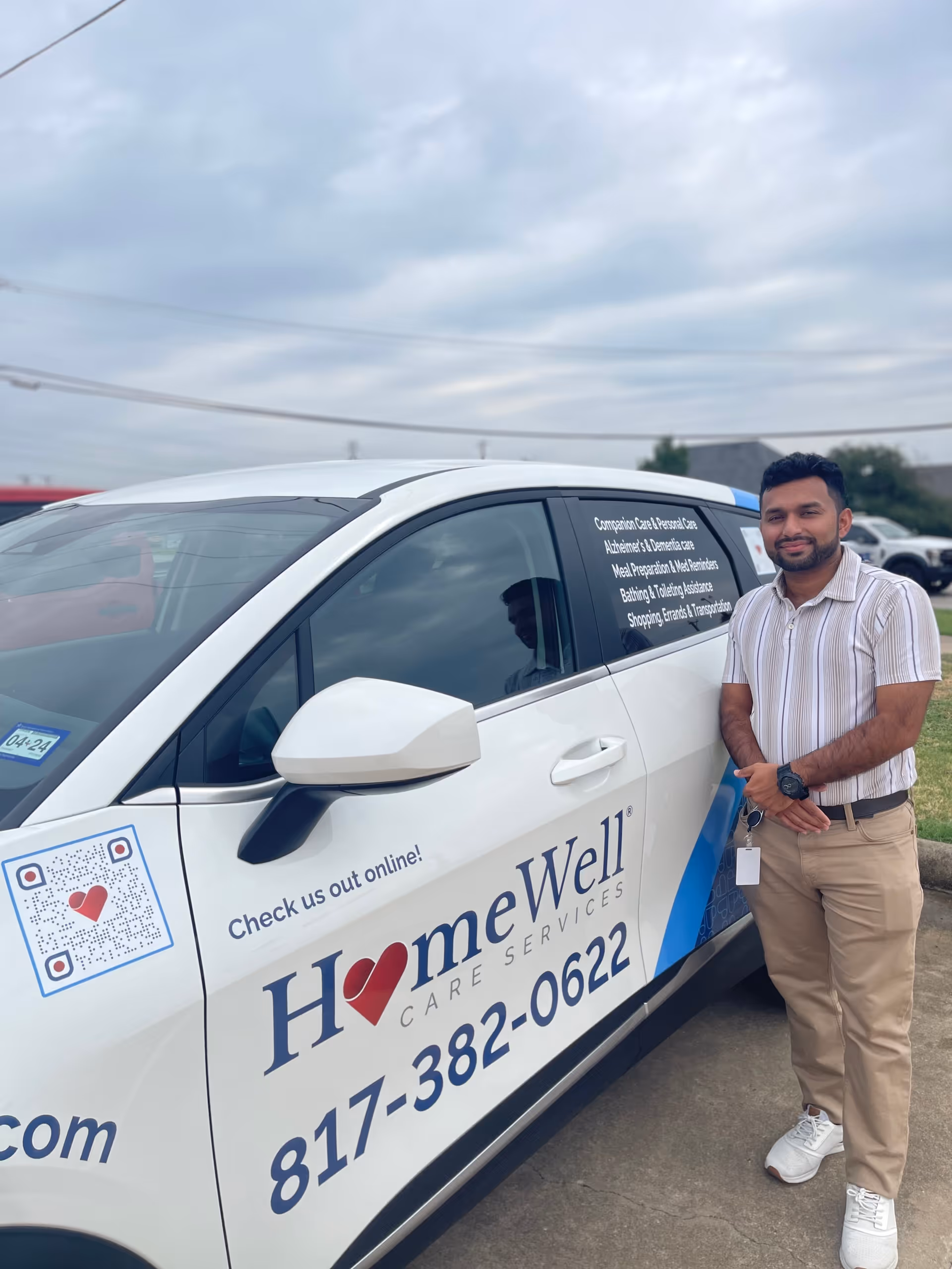 A man stands beside a white HomeWell Care Services van outdoors.