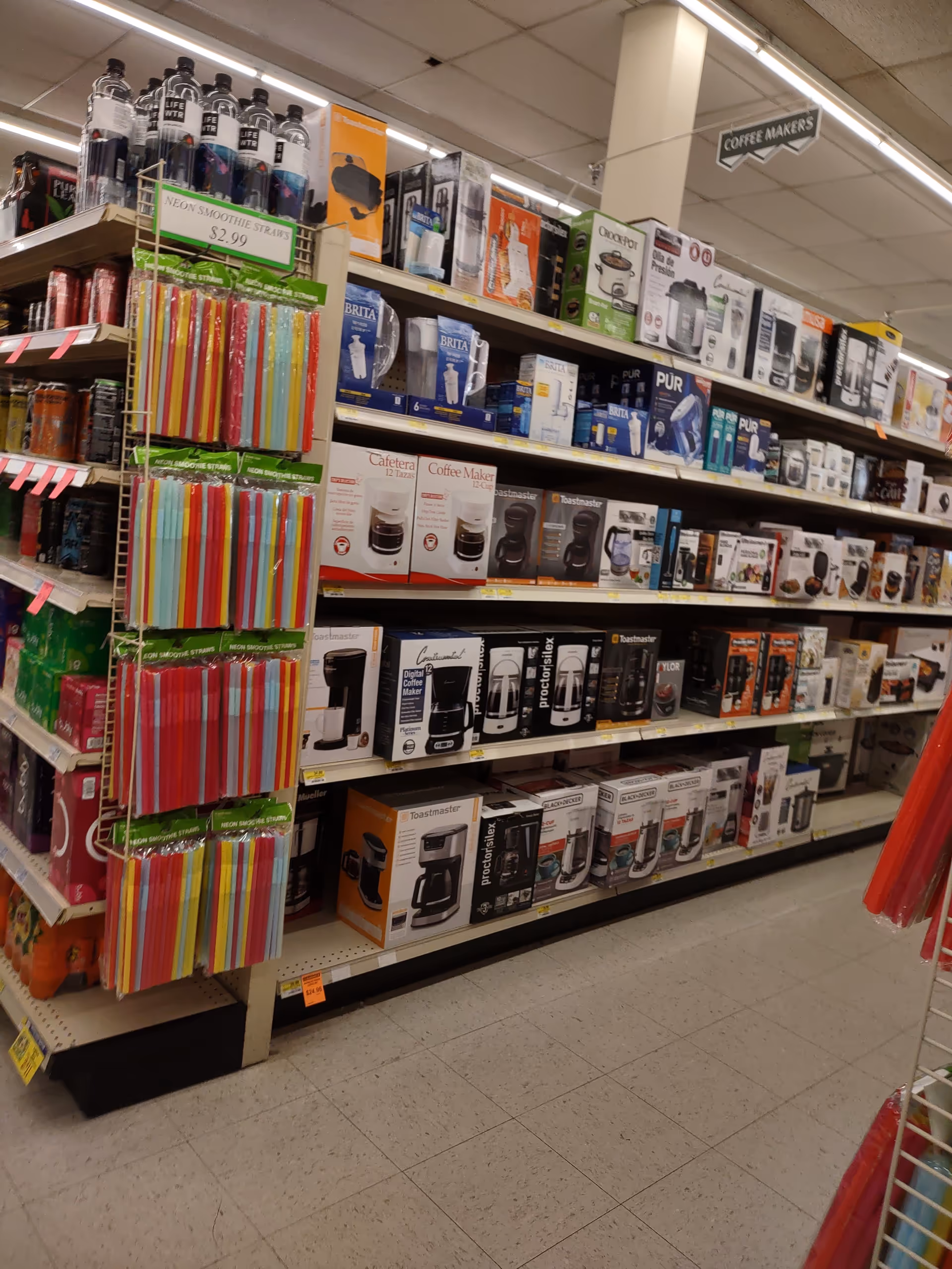 Aisle of boxed kitchen appliances and coffee makers on shelves at Discount Drug Mart.