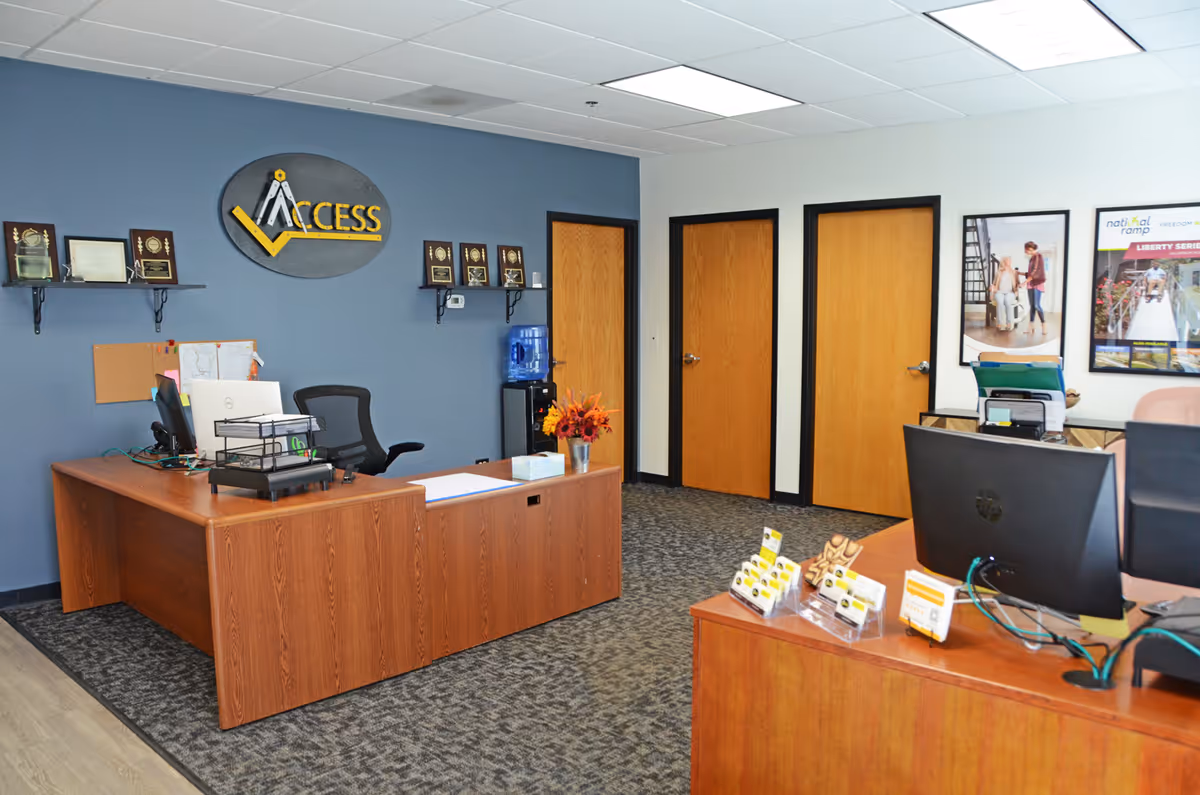 Reception area with wood desks, computers, blue wall logo 'Access', and three doors.