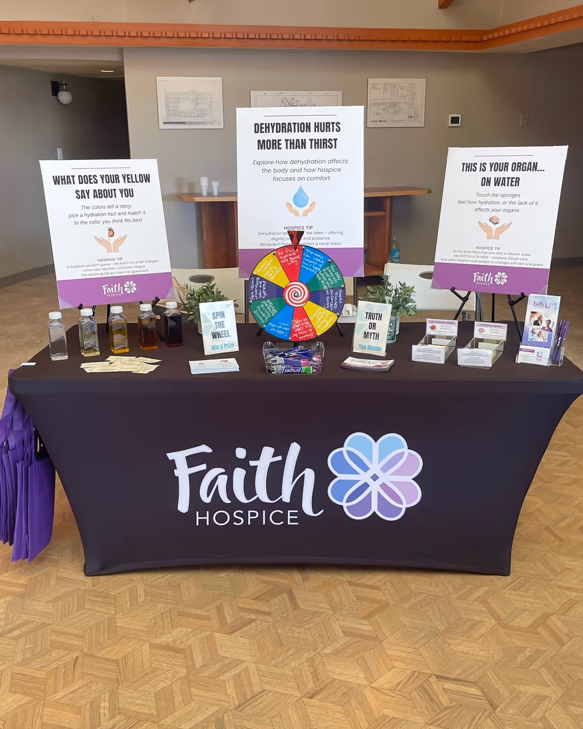 Indoor info table with Faith Hospice branding, posters, wheel, and brochures.