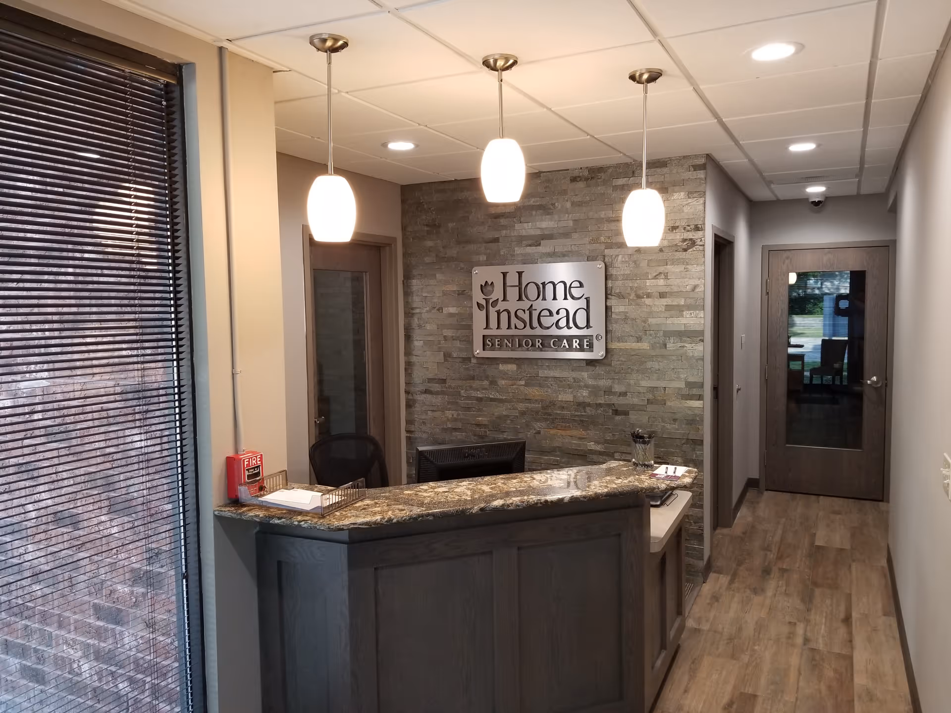 Reception desk in a modern lobby with a stone wall and Home Instead sign.