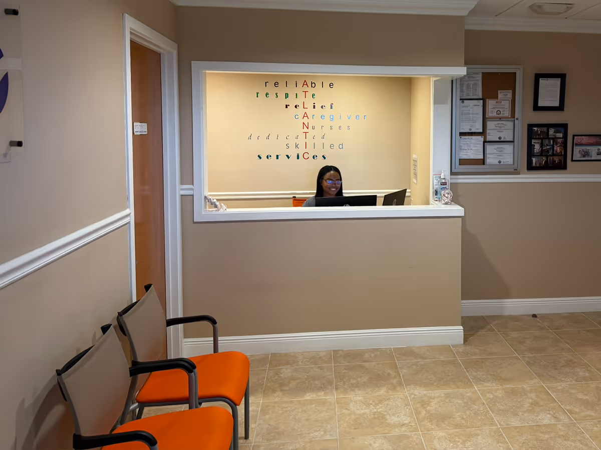 Reception area with beige walls, waiting chairs, and a staff member at the counter.
