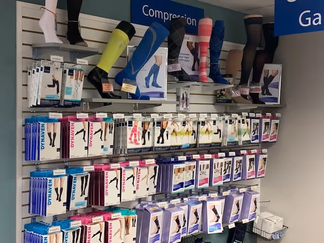 Retail display of compression stockings and leg-support products on wall shelves.