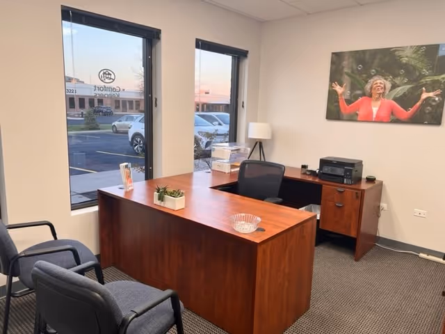 Wooden desk with chairs and office equipment in a small reception-style interior.