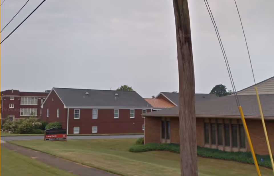 Exterior view of LINCARE senior living campus with brick buildings and a green lawn.