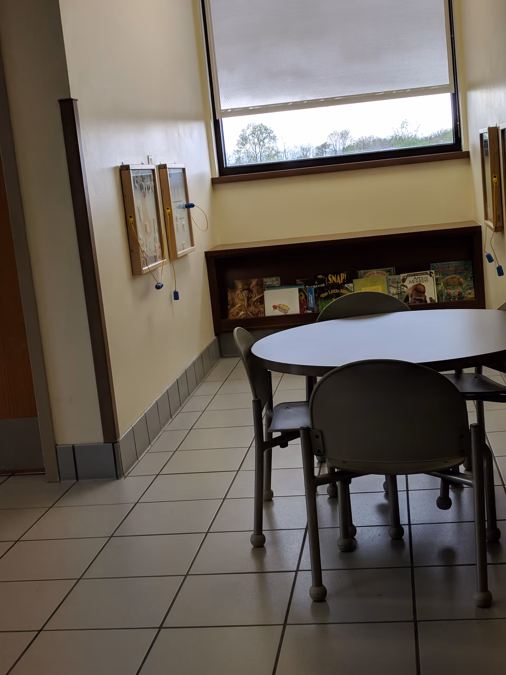 Interior dining area with a round table, chairs, and a magazine shelf.