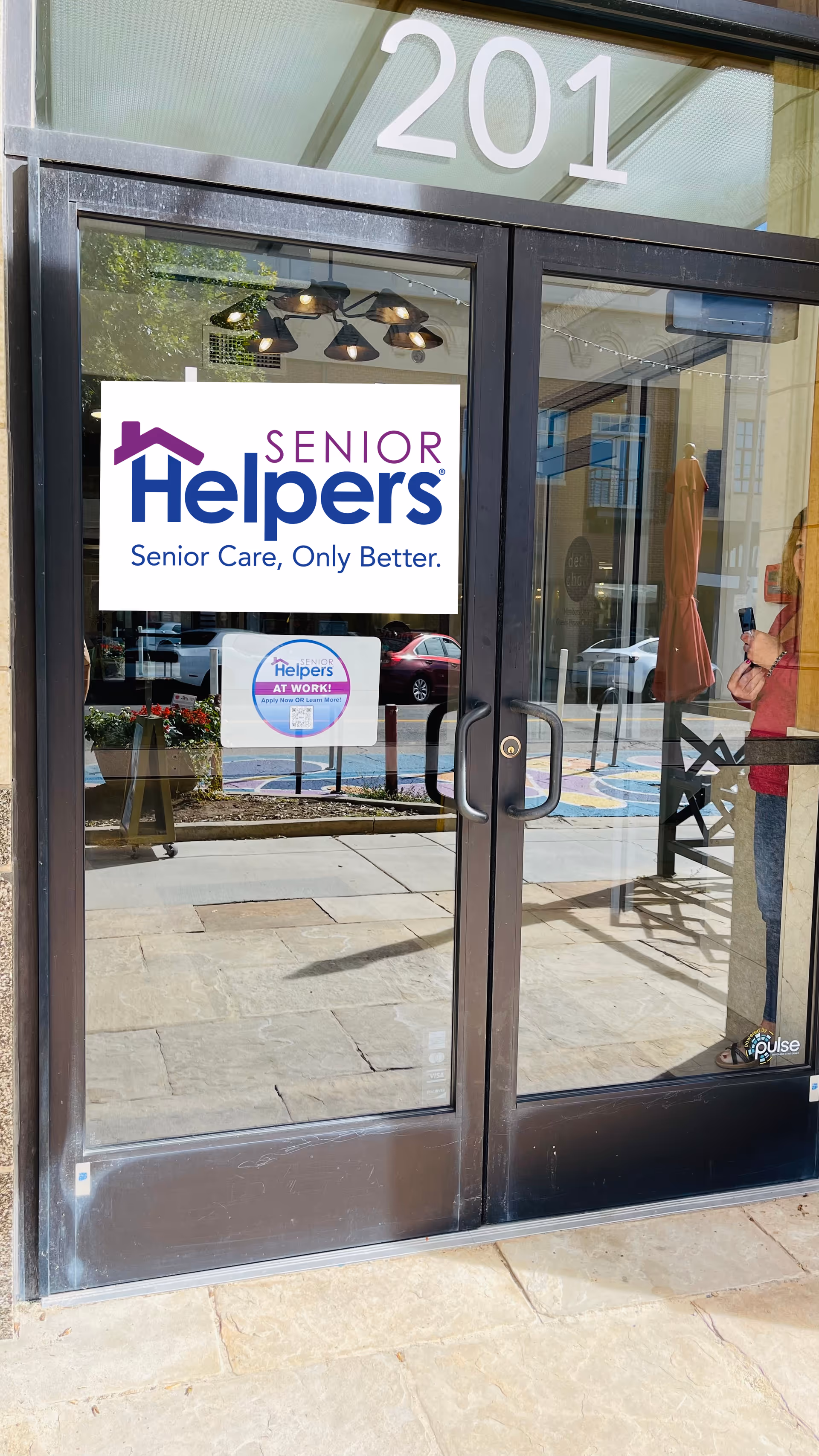 Glass storefront door with Senior Helpers sign and building number 201