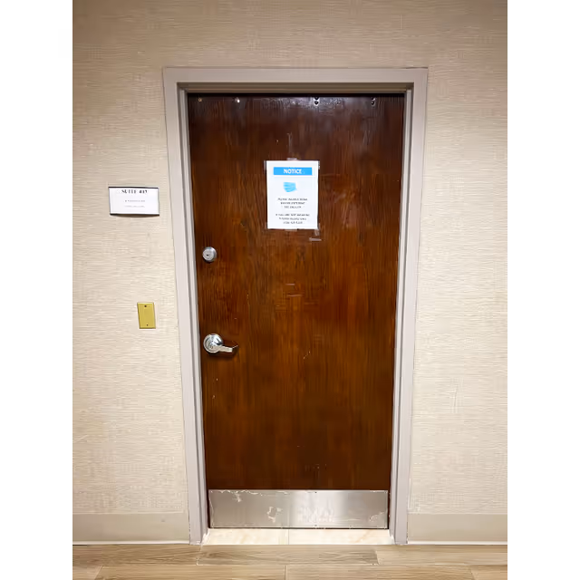 A wooden interior door with a posted notice in a hallway.