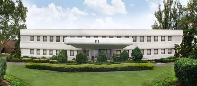 White curved-front building with manicured lawn and trimmed hedges.