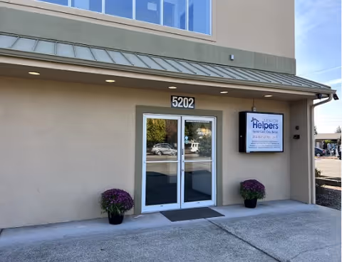 Front exterior of Senior Helpers facility entrance with double doors and potted plants.