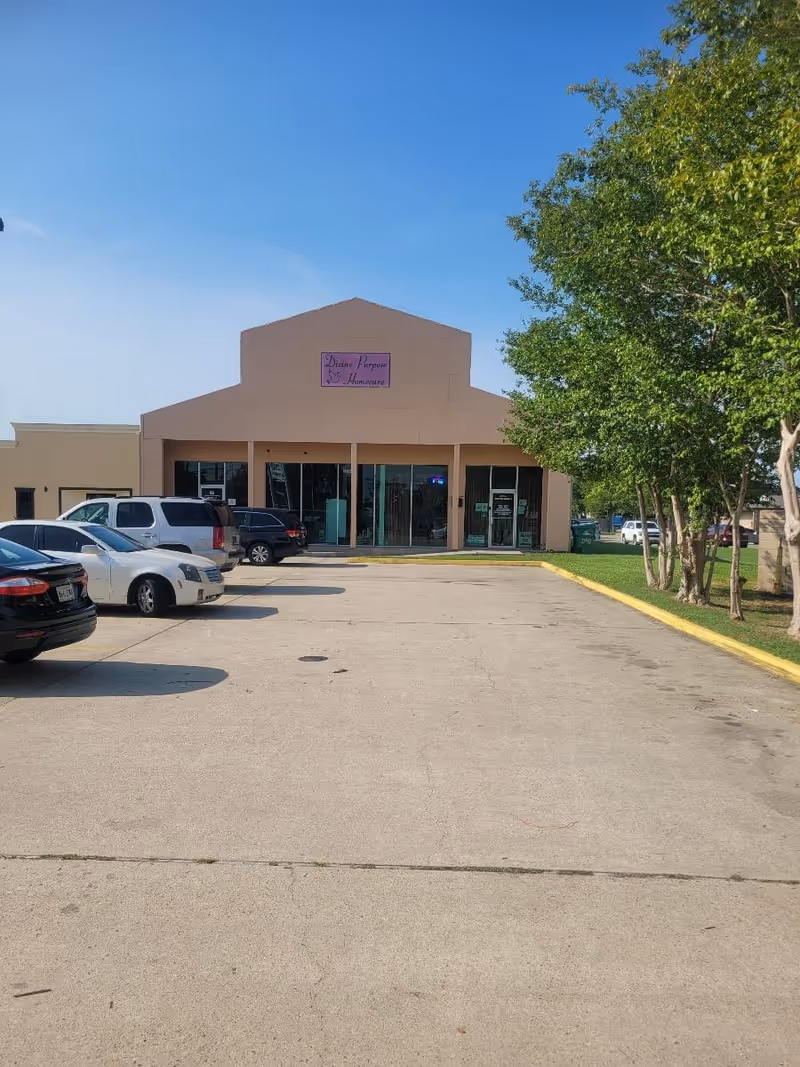 Front view of a beige senior care facility with Divine Purpose Home Care sign and parking.