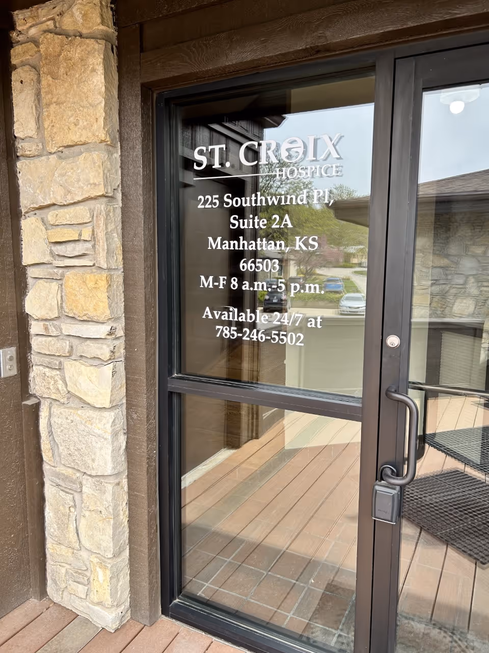 Glass door of St. Croix Hospice entrance with stone and wood exterior.