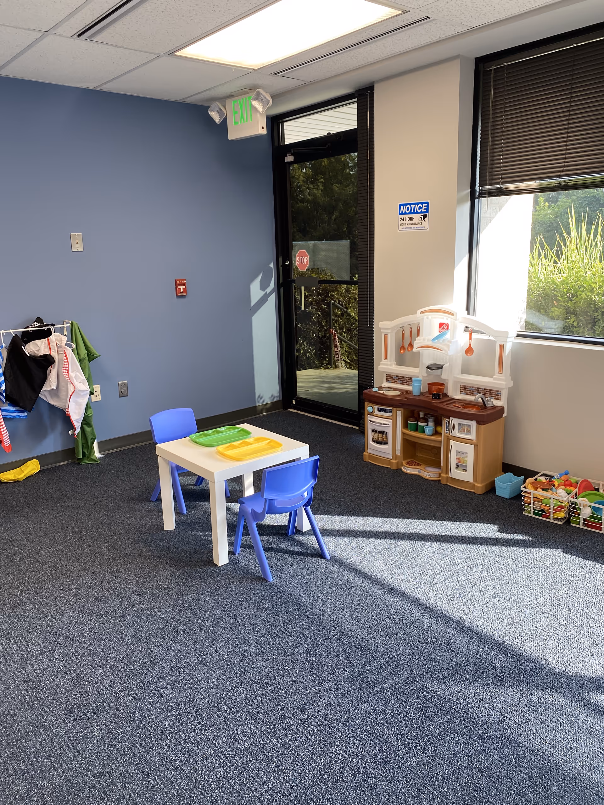Indoor children's playroom with a small table, blue chairs, and toy kitchen.