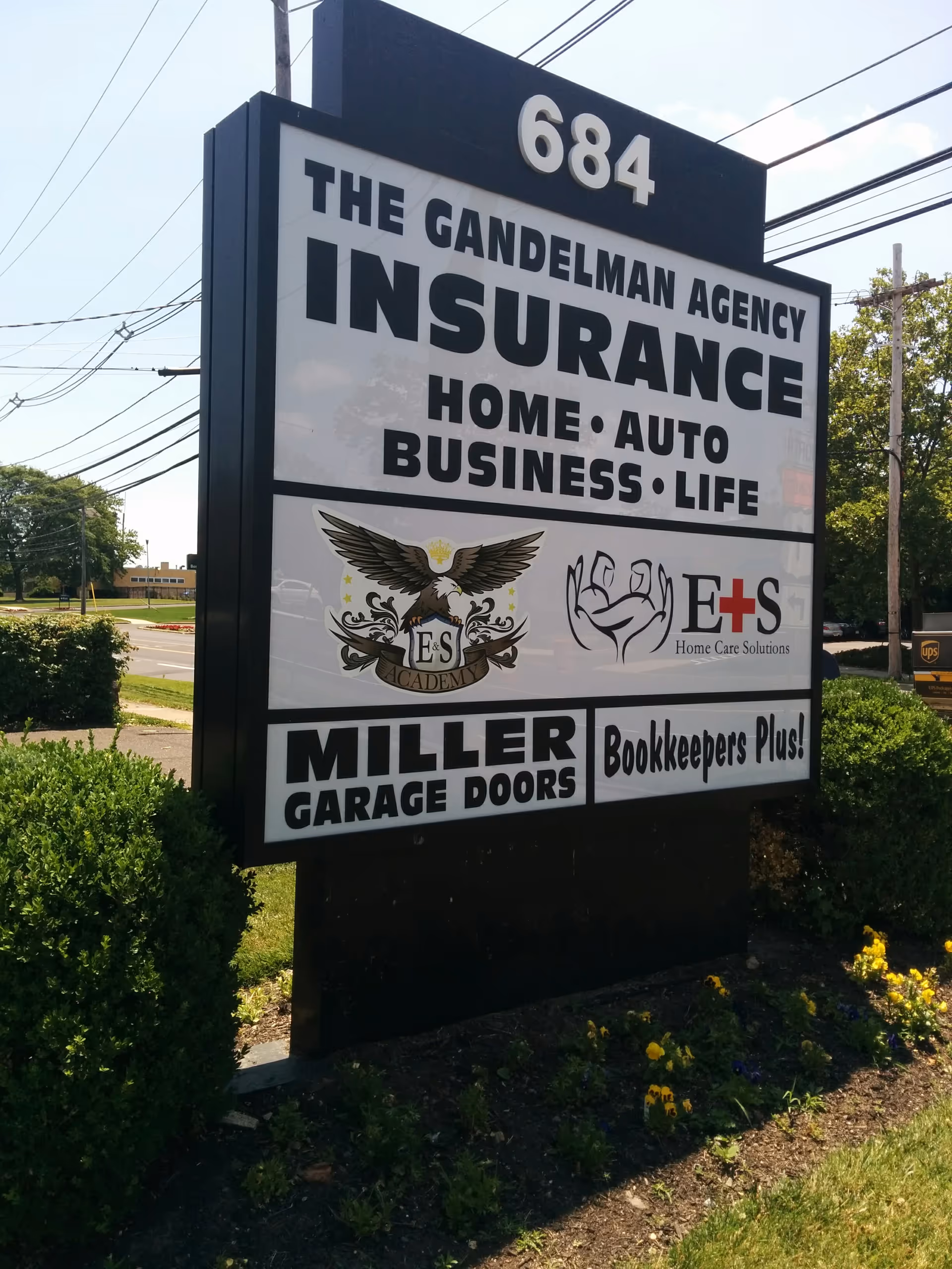 Outdoor signboard advertising insurance and home care services with greenery.