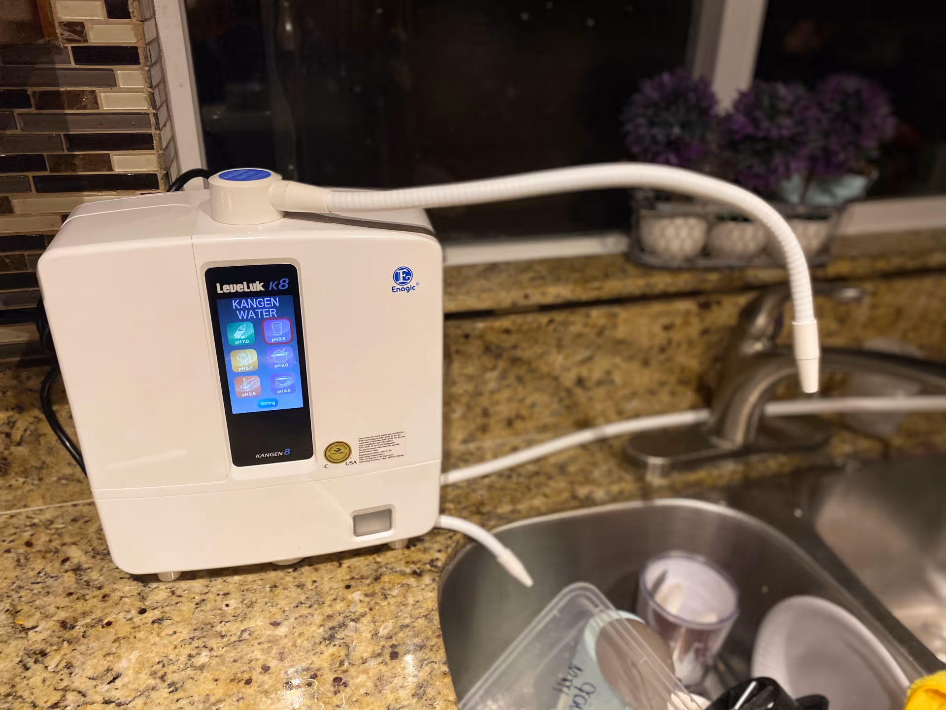 White water purification device on a granite kitchen counter beside the sink.