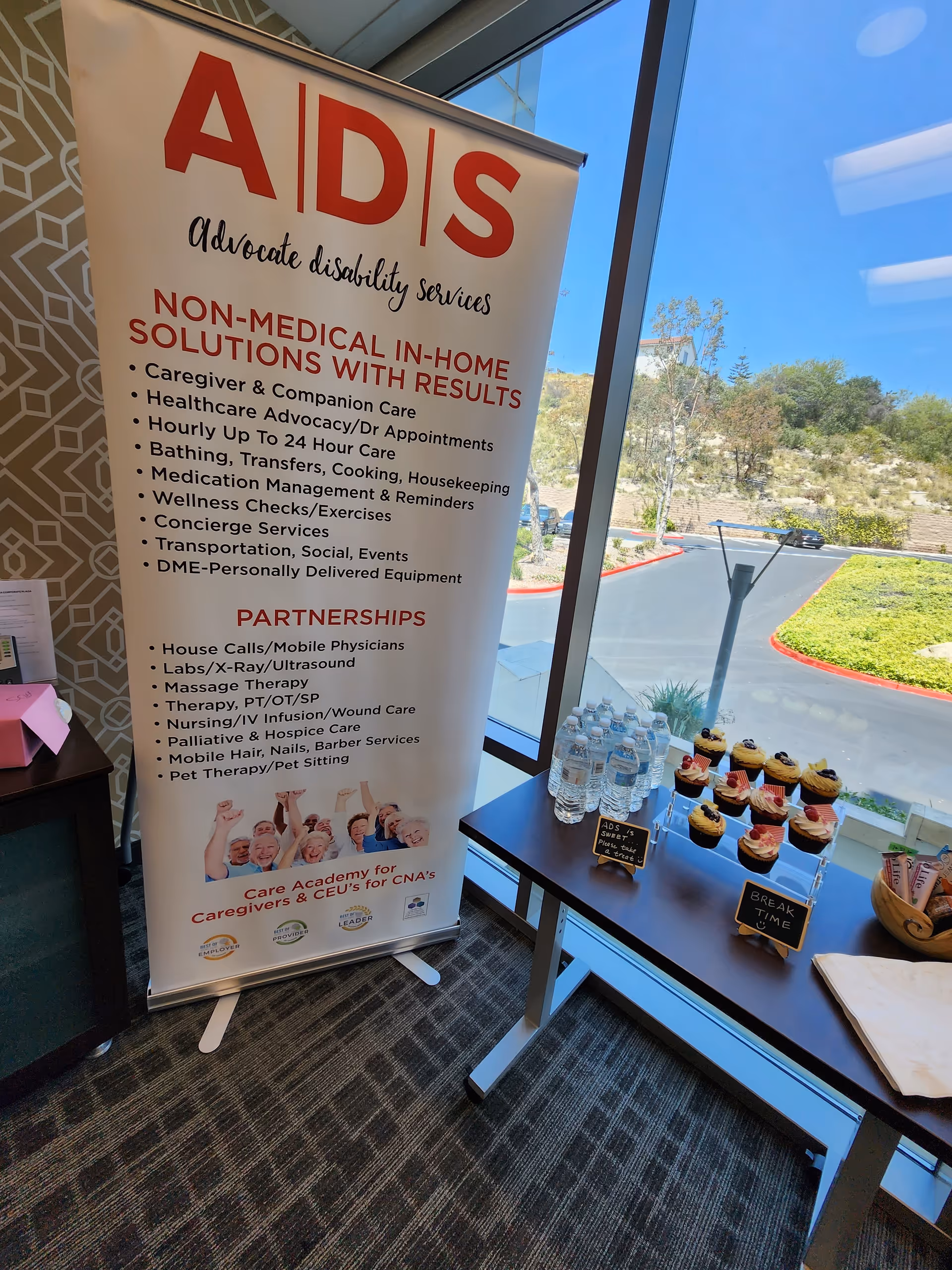 Promotional banner for ADS Advocate Disability Services beside a table with water and cupcakes.
