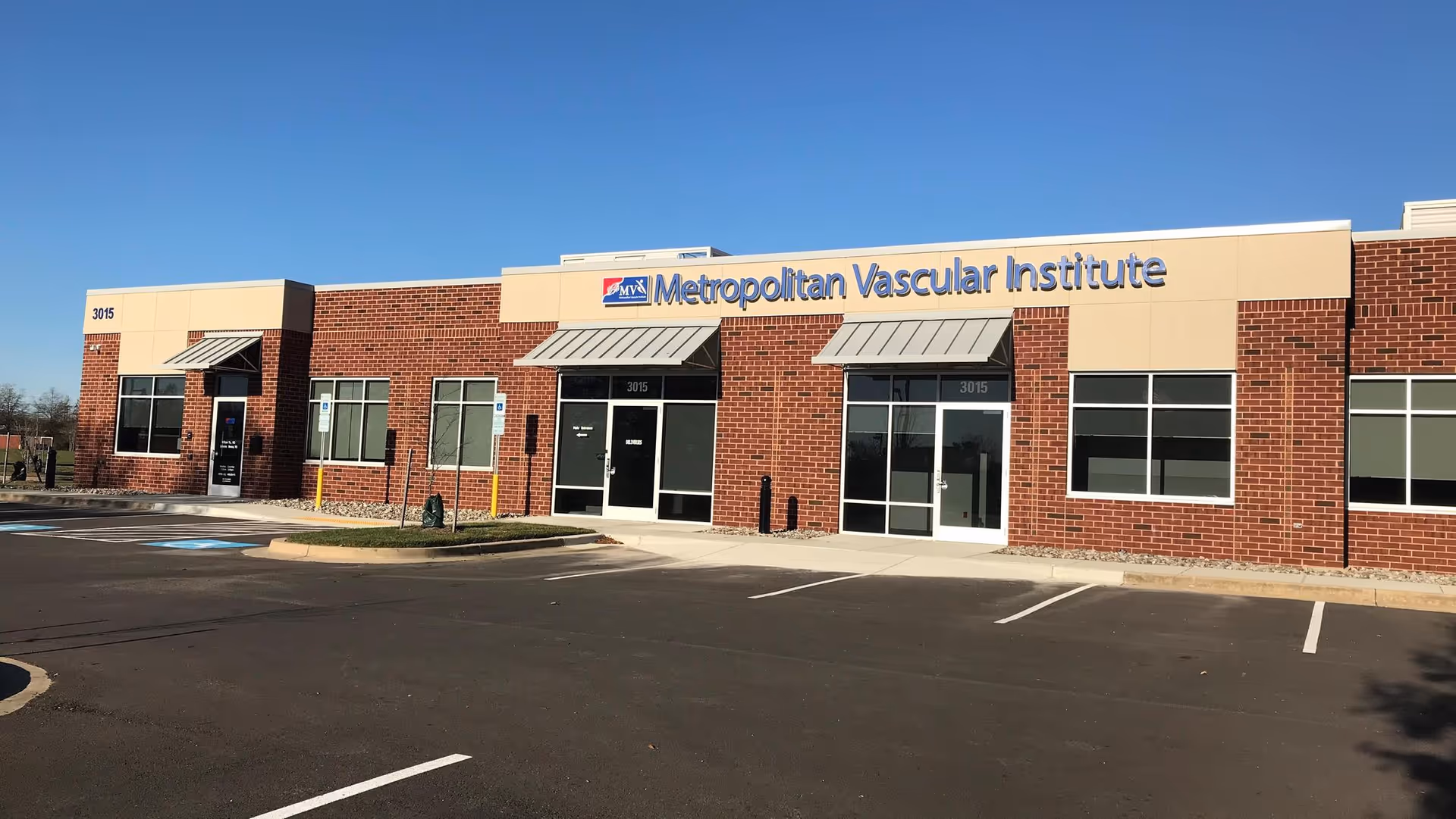 Exterior view of Metropolitan Vascular Institute building with parking lot and clear sky