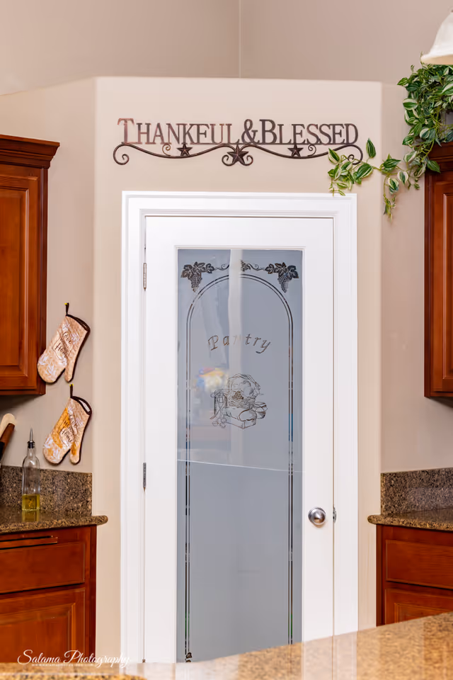 Interior kitchen area featuring a glass-paneled pantry door and a decorative 'Thankful & Blessed' sign.