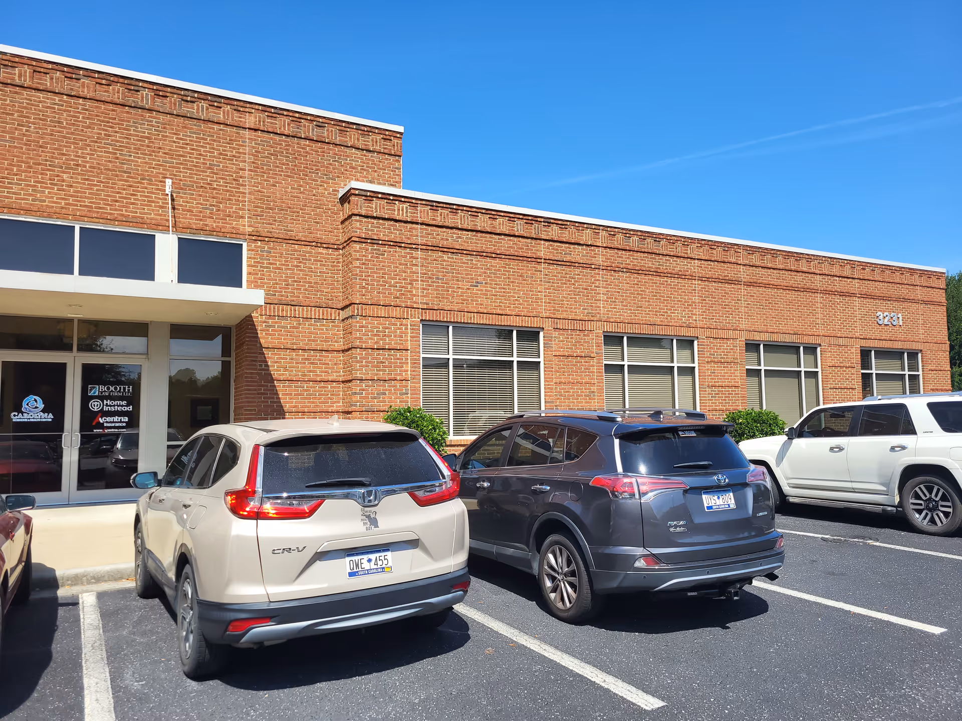 Brick exterior of Home Instead facility with parked cars outside and large windows.