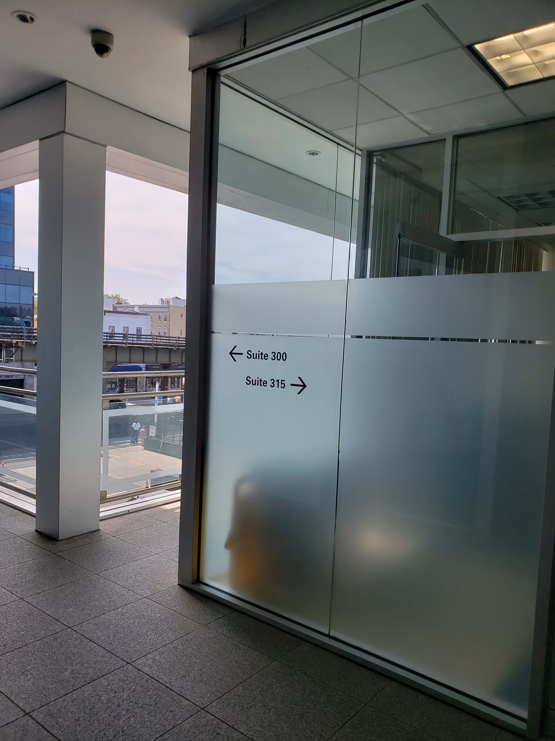 Indoor corridor with glass partition and frosted doors labeled Suite 300 and Suite 315.