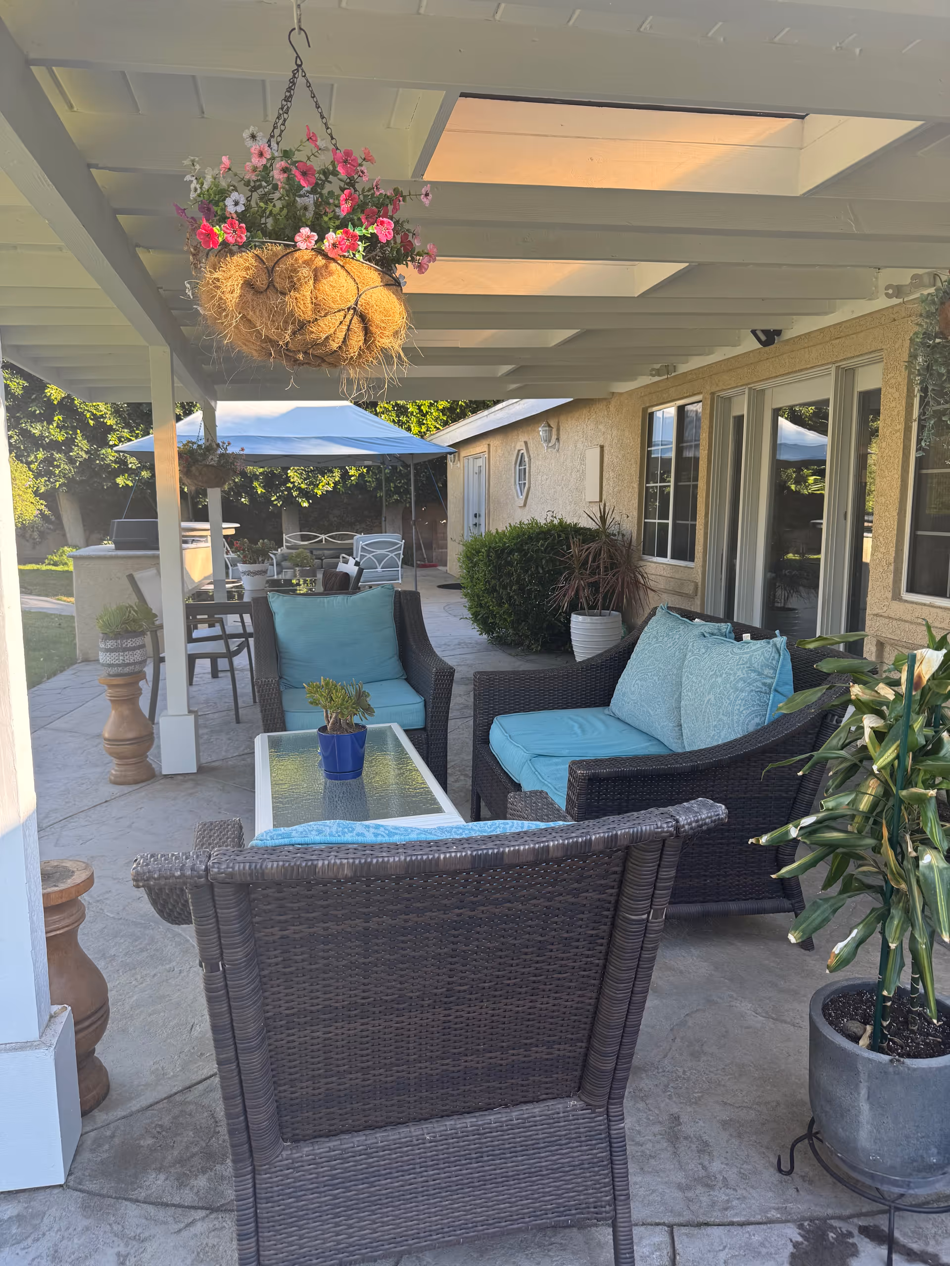 Outdoor patio seating under a covered area with hanging flowers.