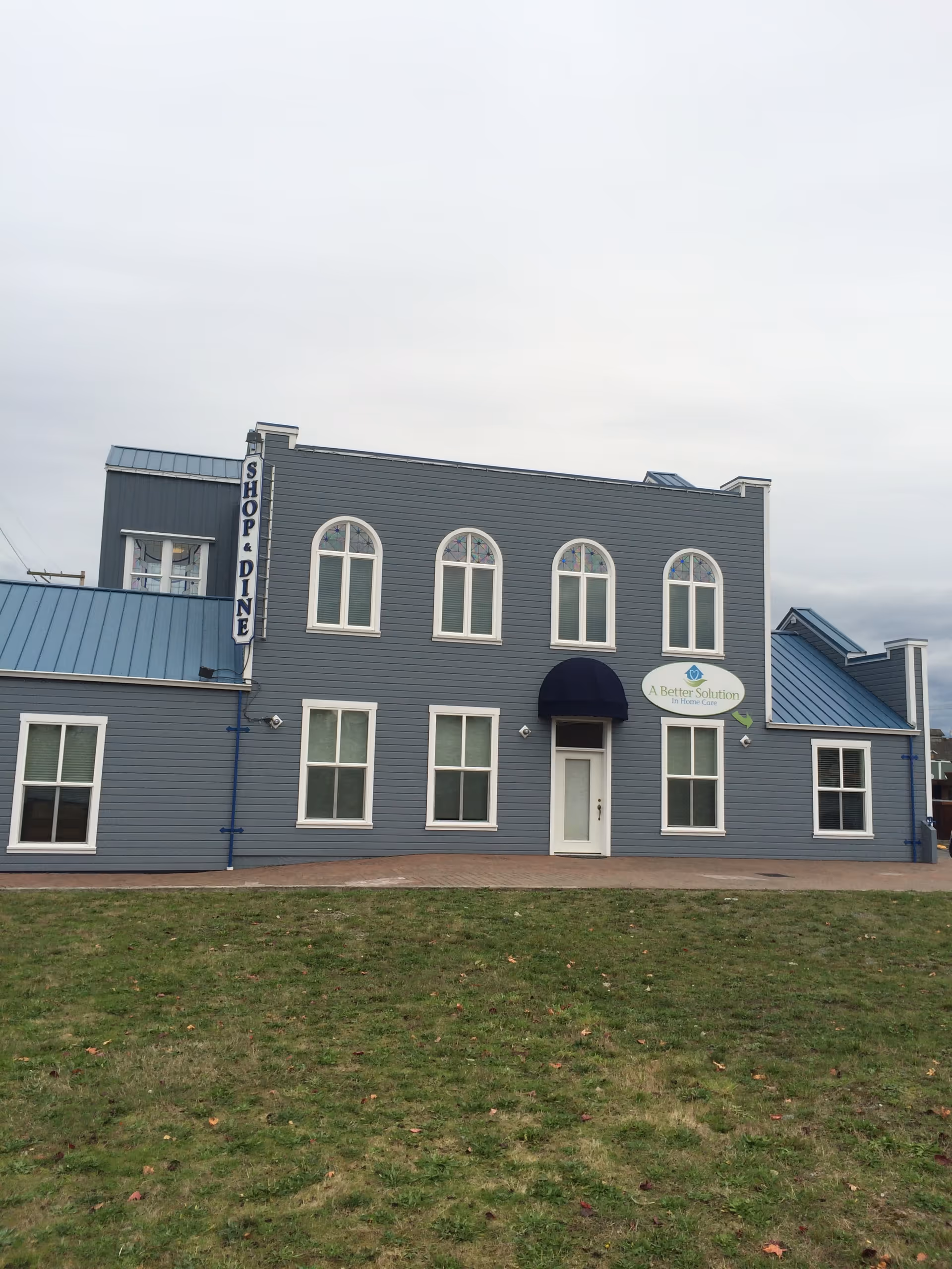 Blue two-story building with arched windows and a sign for A Better Solution In Home Care.