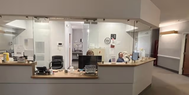Reception area of Abbey Hospice with glass-front desk and staff at computers.