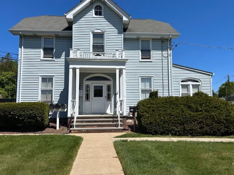 Light blue two-story house with white trim and a covered entryway.