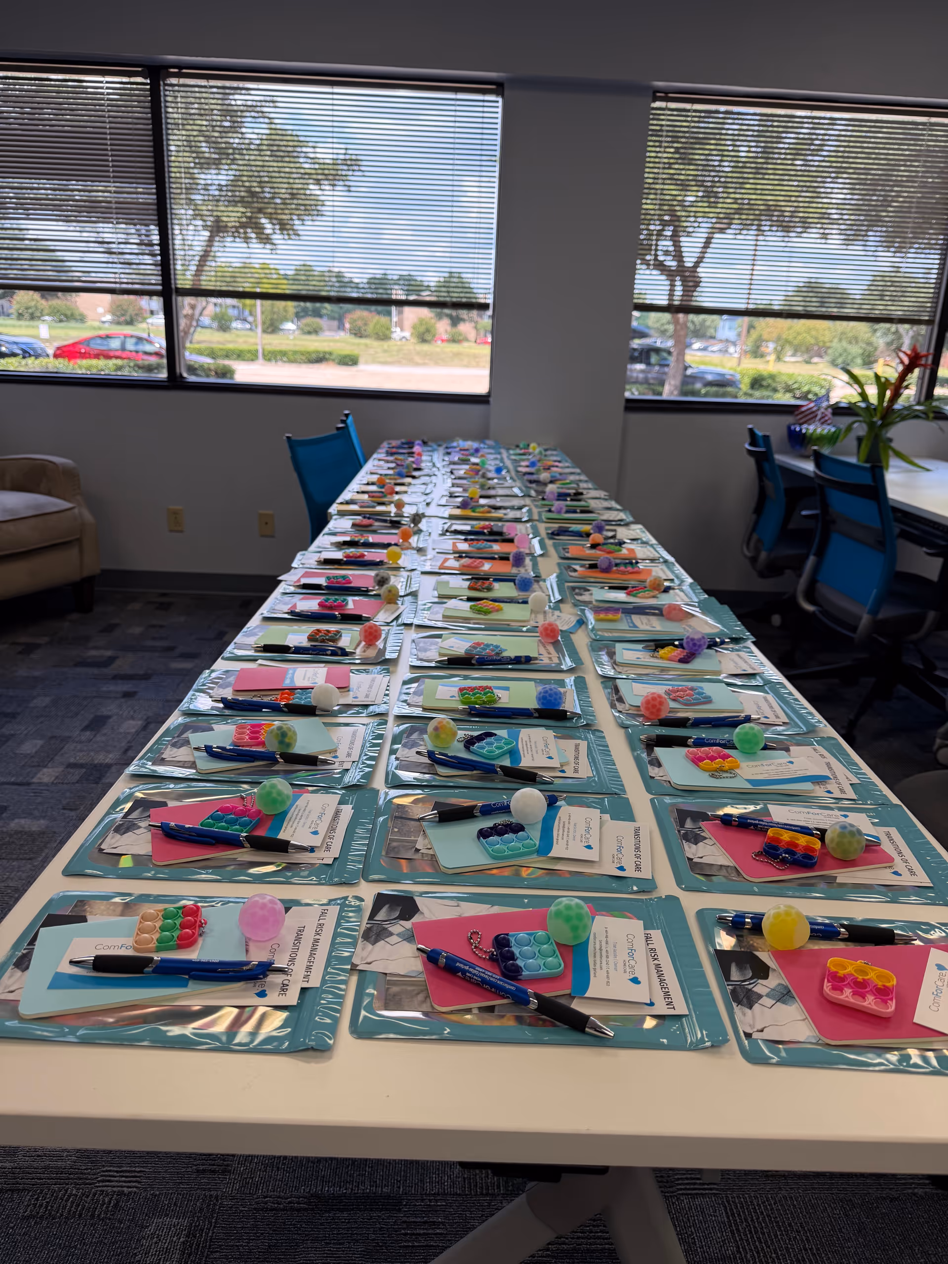 Long table set with colorful place mats, utensils, and small activities in a bright room.