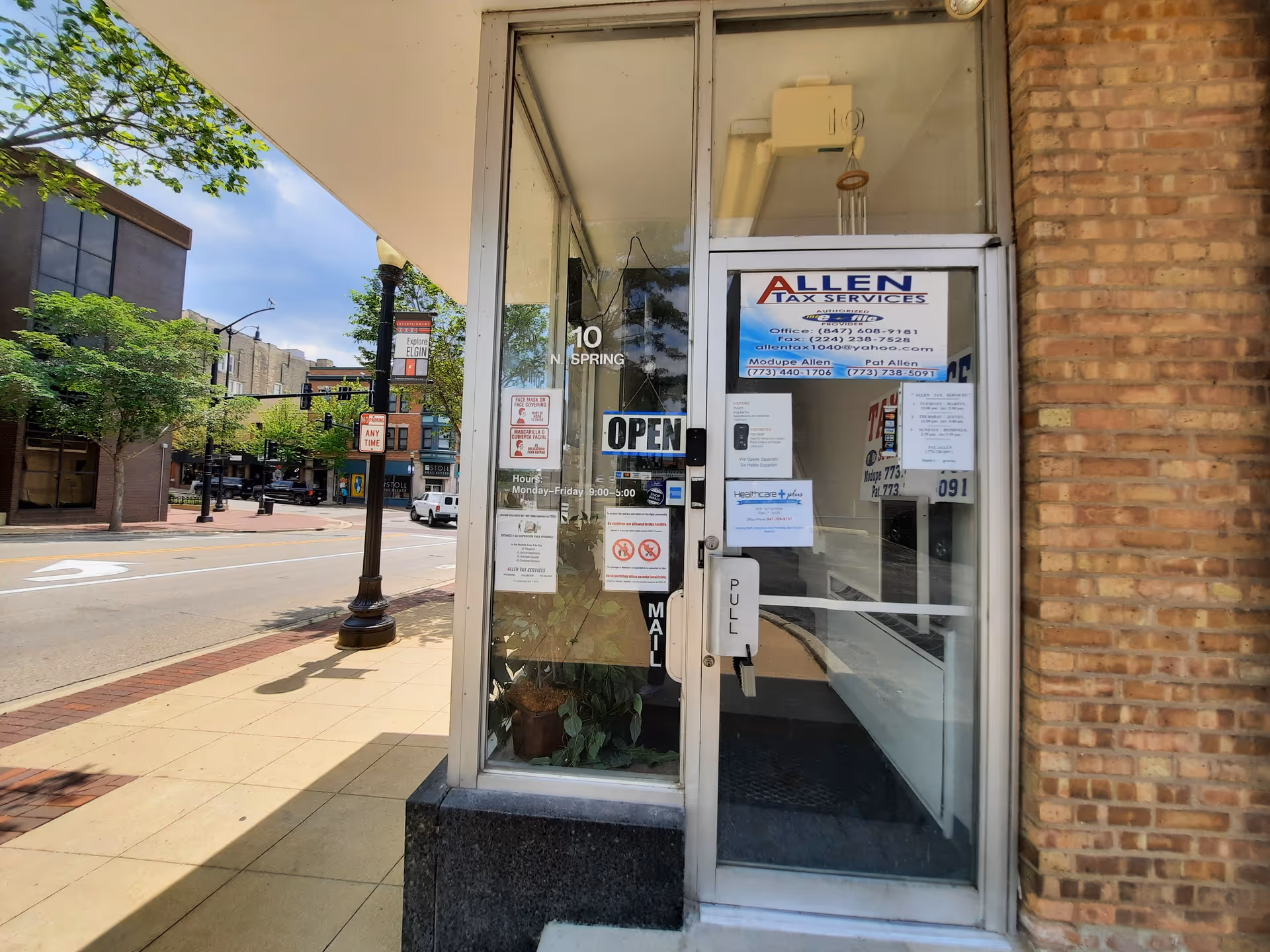 Street-level storefront with glass door, brick wall, and posted signs.