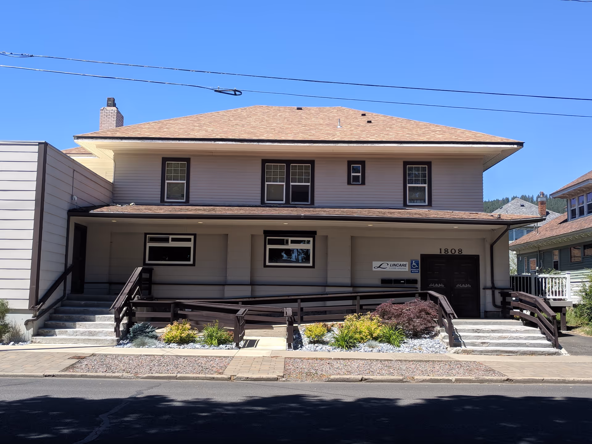 Two-story beige building with wheelchair ramp and LINCARE sign on a sunny day.