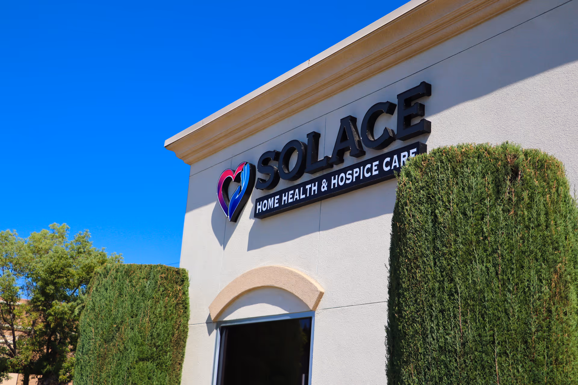 Front exterior of a building with Solace sign and trimmed hedges