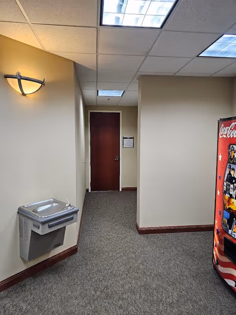 Interior hallway in a senior living facility with a drinking fountain and vending machine.
