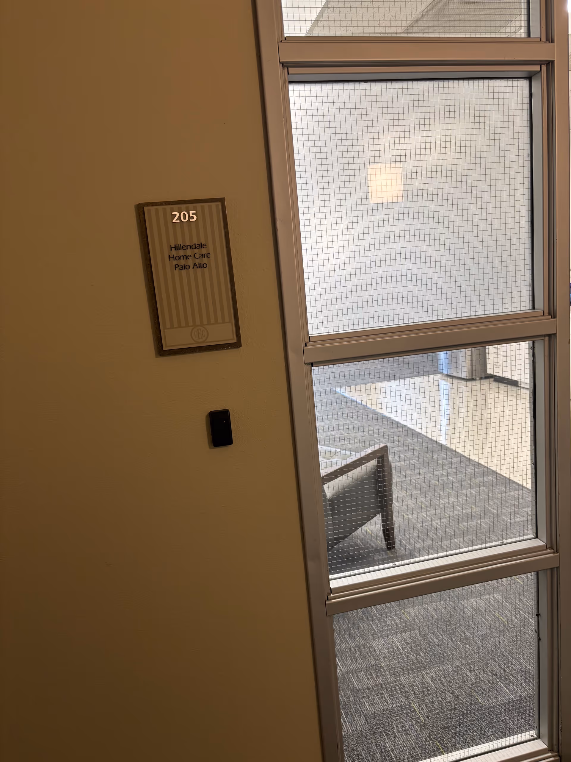 Interior hallway with plaque reading 205 and Hillendale Home Care beside a windowed wall.