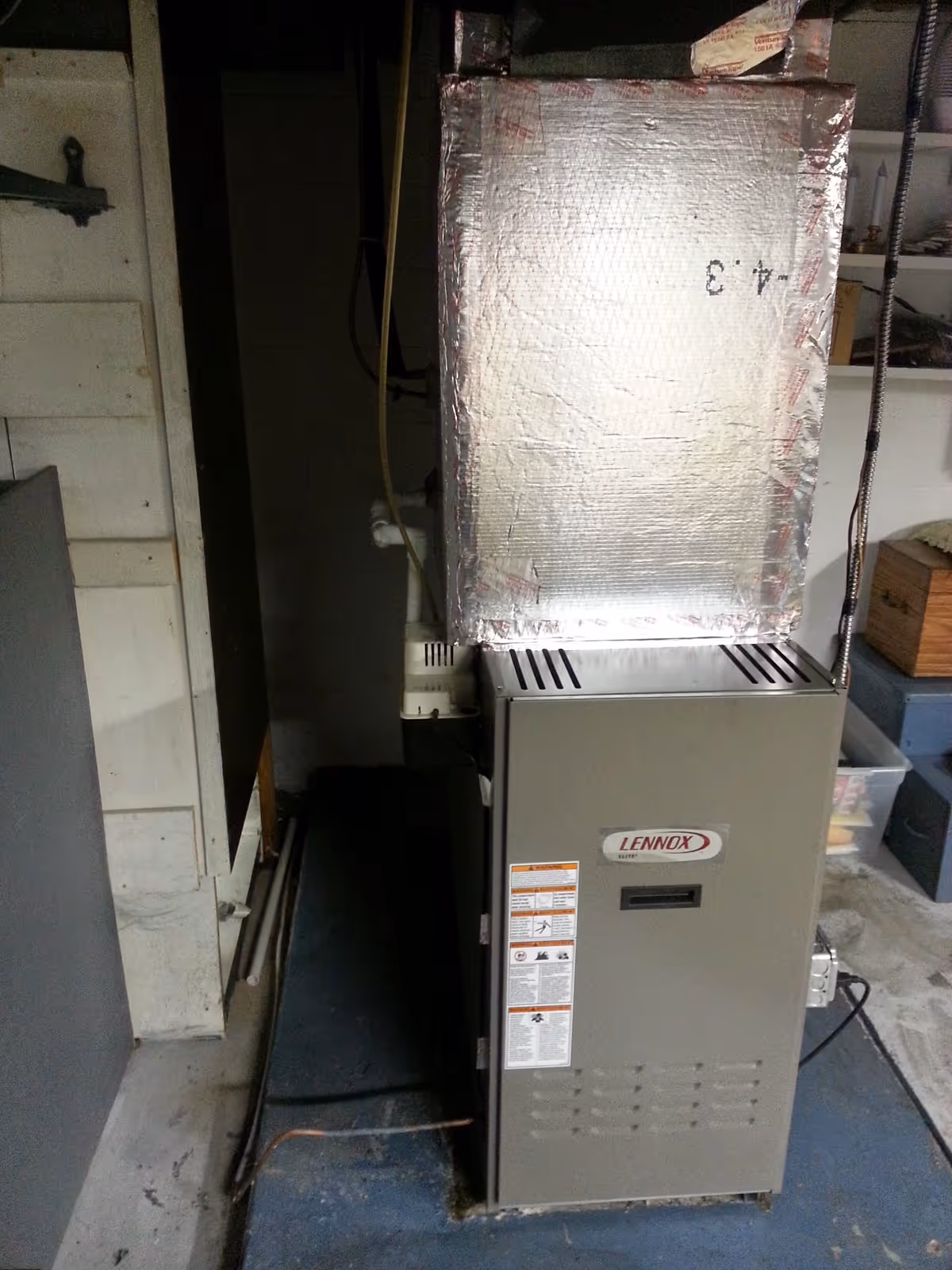 A Lennox furnace in a utility room with insulated ducts and shelves.