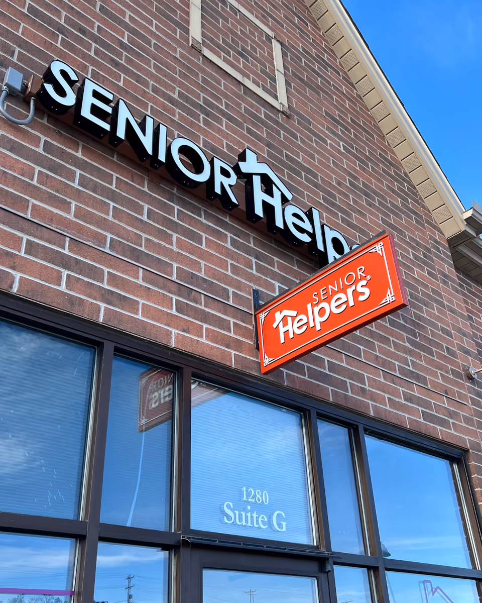 Brick exterior of Senior Helpers building with red signage and windows.