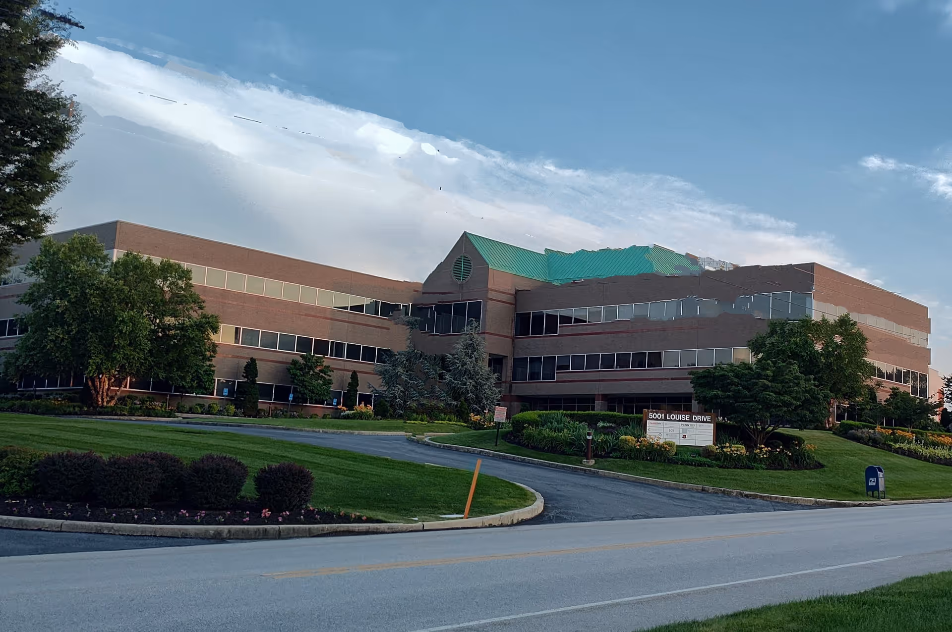 Exterior view of a brick pediatric facility with a green roof and landscaped grounds.