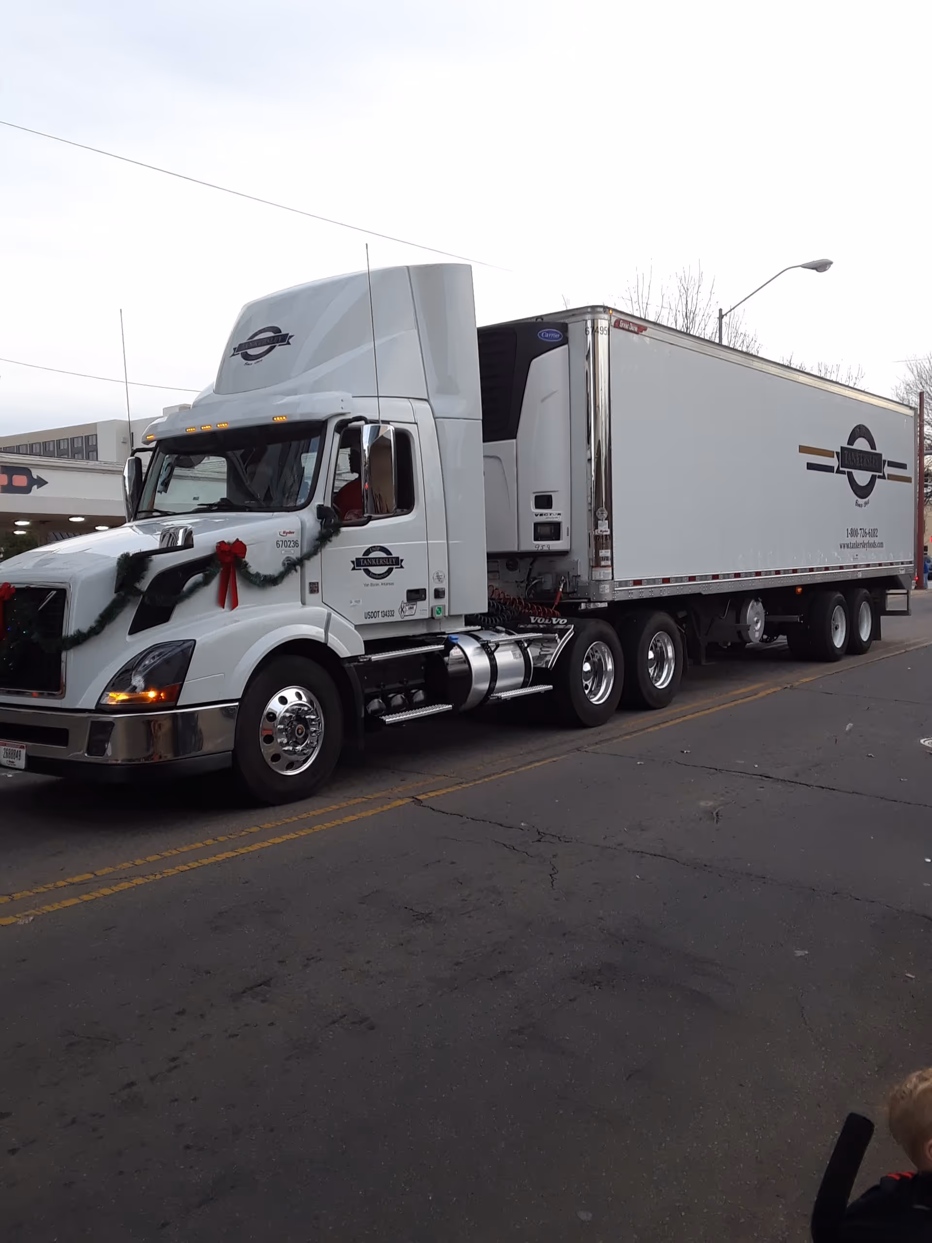 White semi-truck decorated with red ribbons parked on a city street.