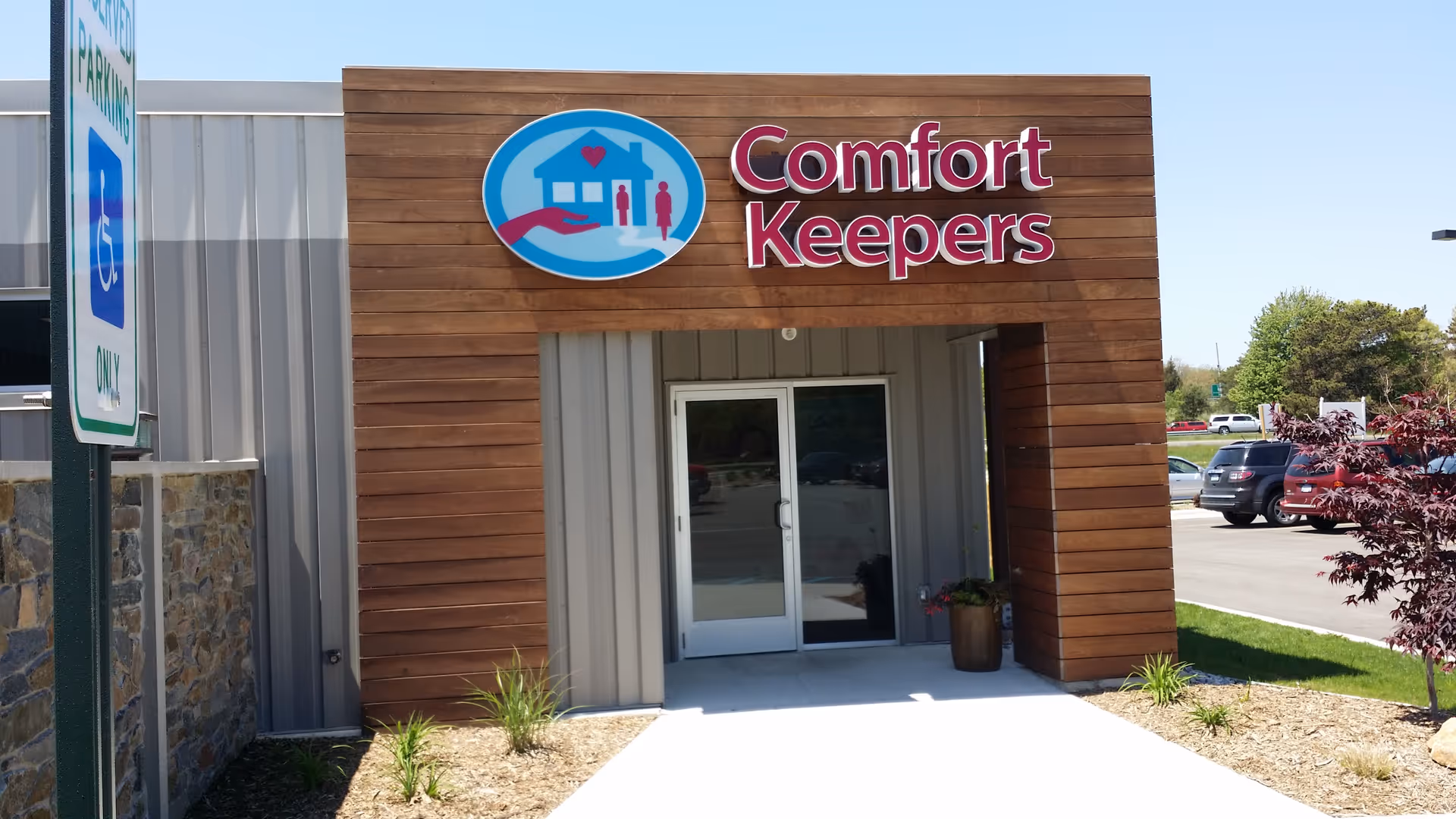 Front entrance of a Comfort Keepers Home Care building with wooden facade and sign.