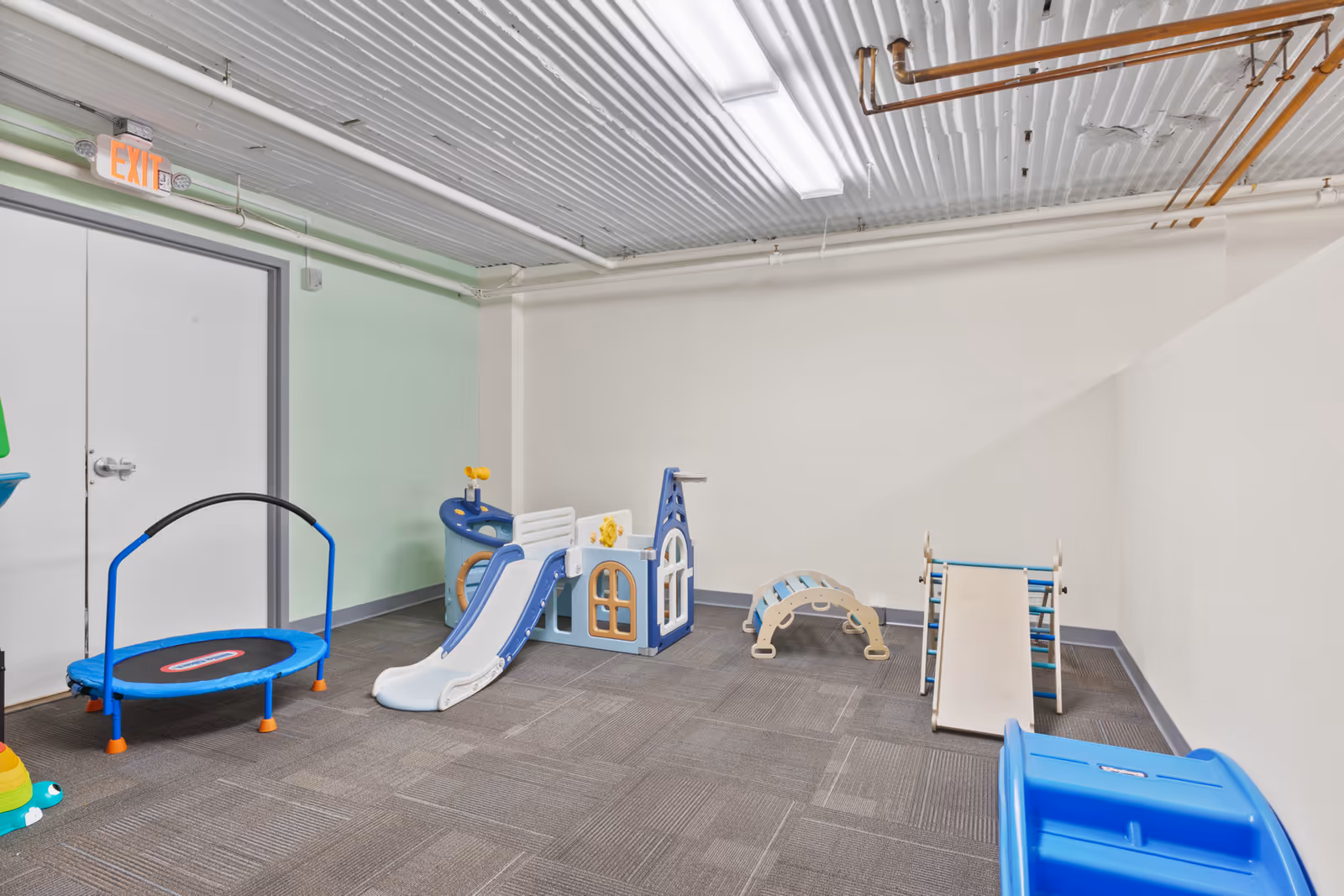Indoor playroom in a senior facility with slides, a trampoline, and climbing toys.