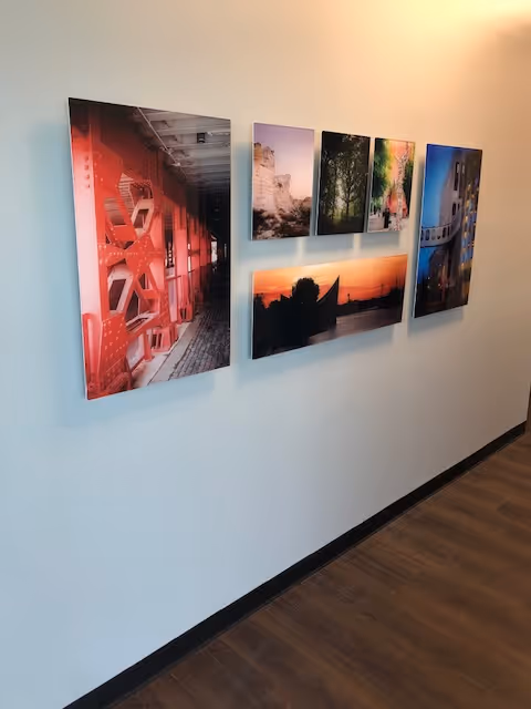A light hallway with multiple framed landscape photos arranged along a blue wall.