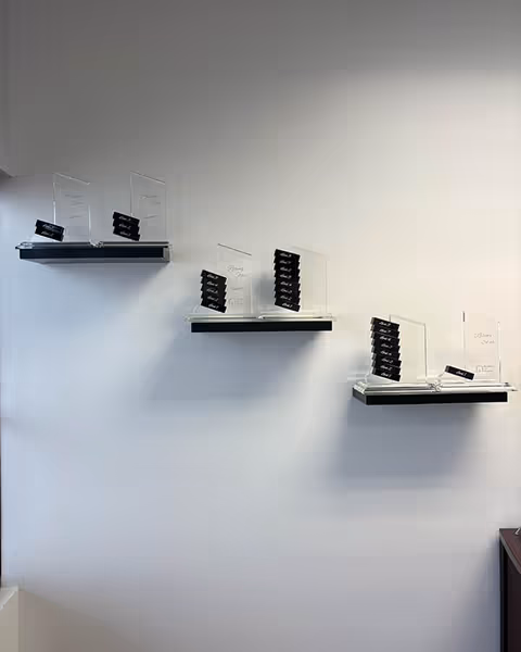 White wall featuring three angled shelves with acrylic card holders and black cards.