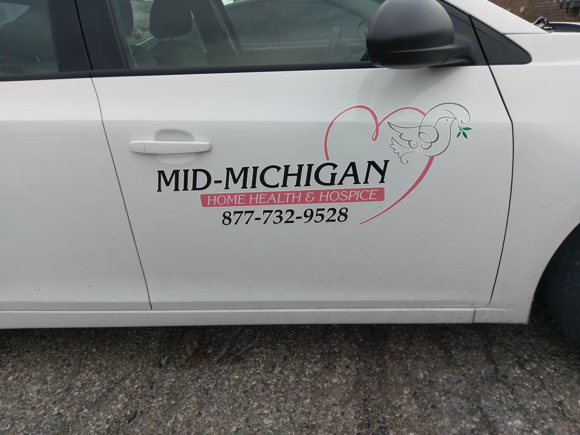 White service vehicle displaying Mid-Michigan Home Health & Hospice logo on door.
